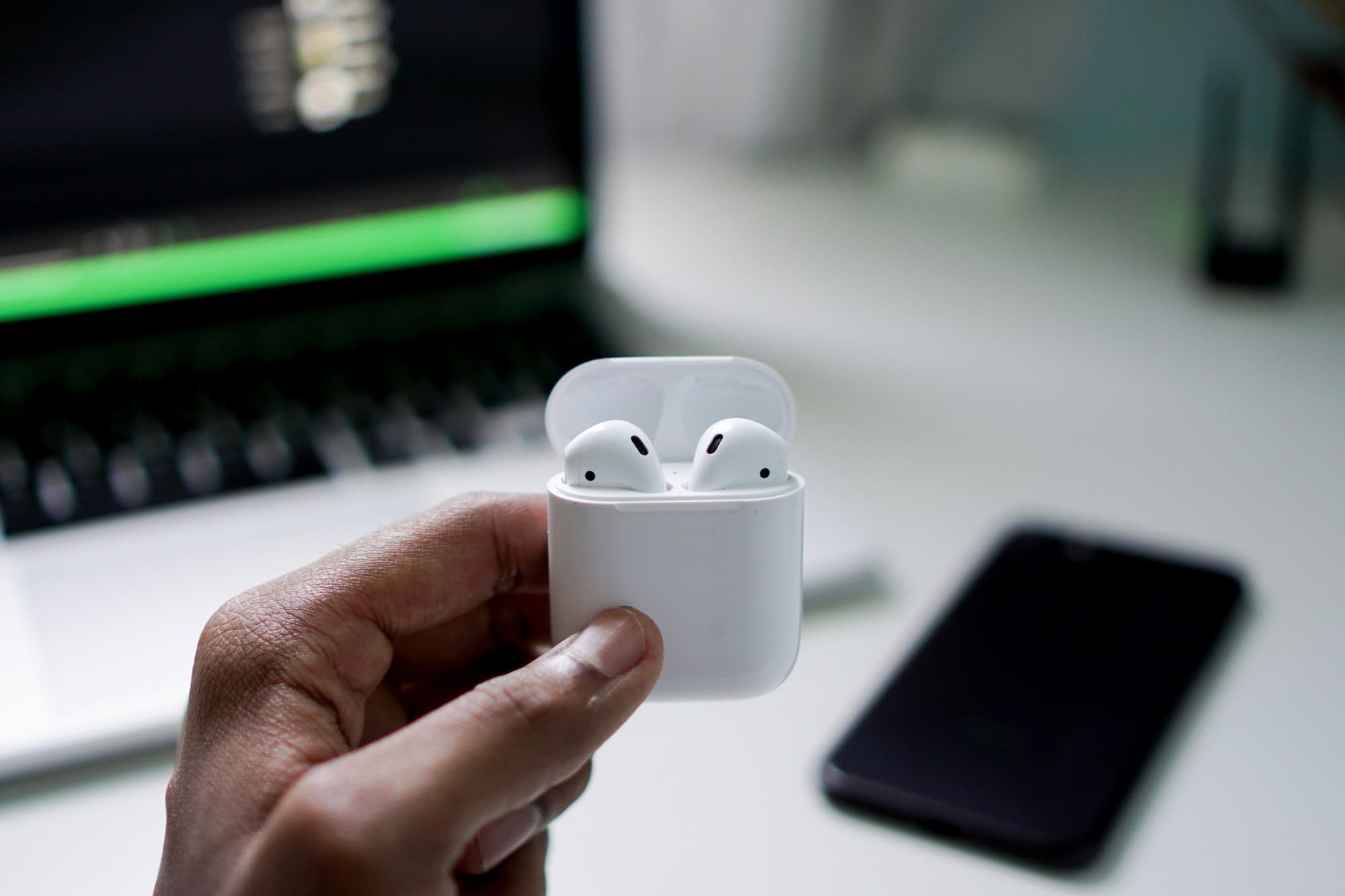 person holding airpods in case