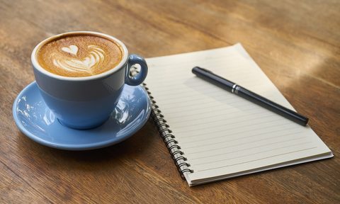 Latte next to a pad of paper and a pen