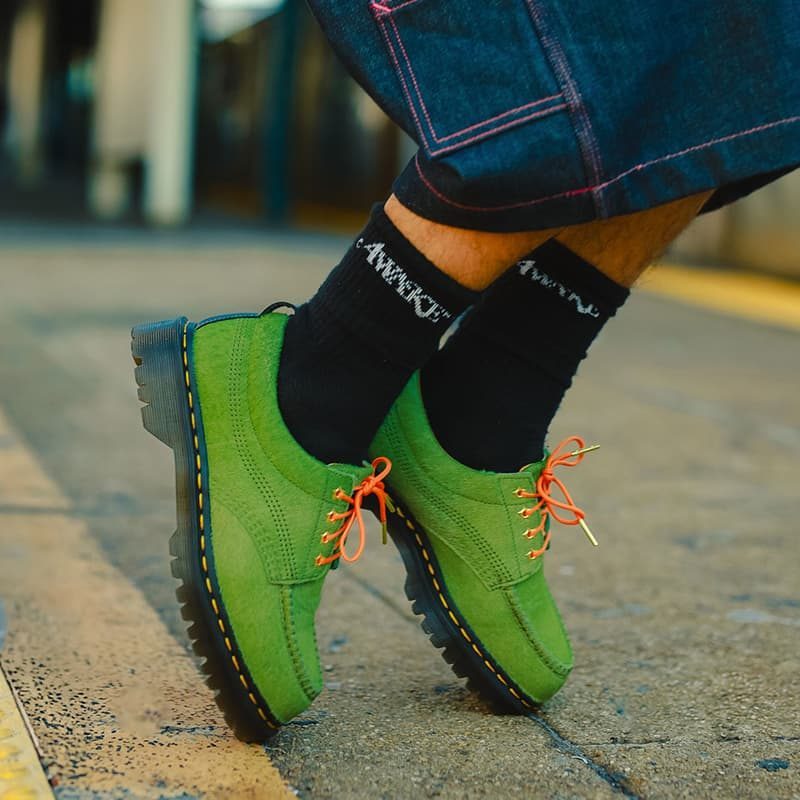 man wearing green dr martens standing on toes