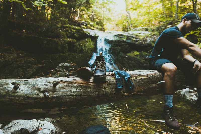 Man taking off his boots by the river