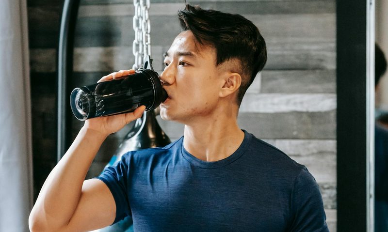 Man in gym taking supplement drinking protein shake powder electrolyte mineral