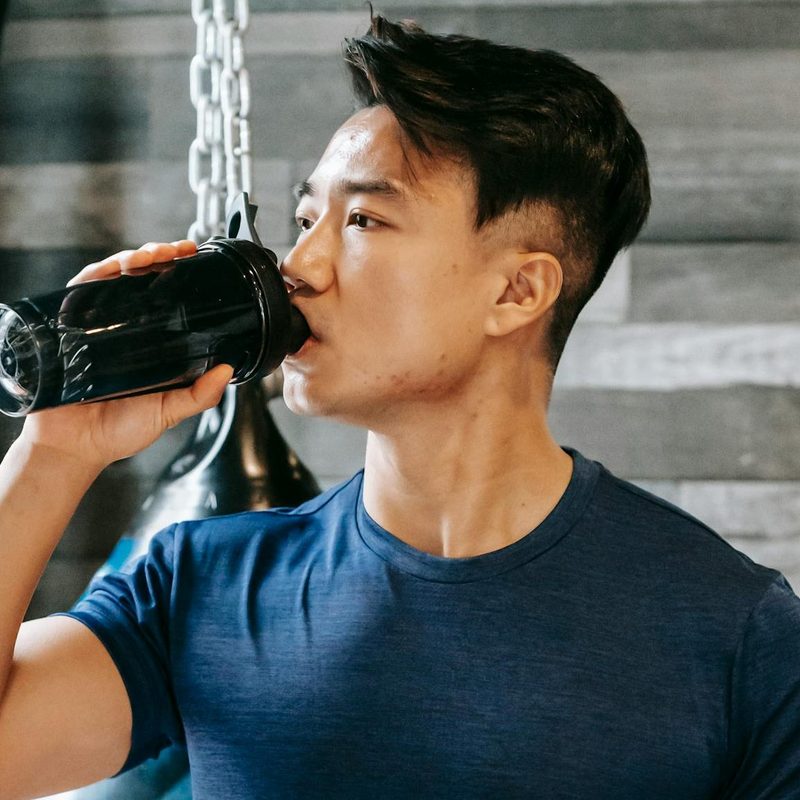 Man in gym taking supplement drinking protein shake powder electrolyte mineral