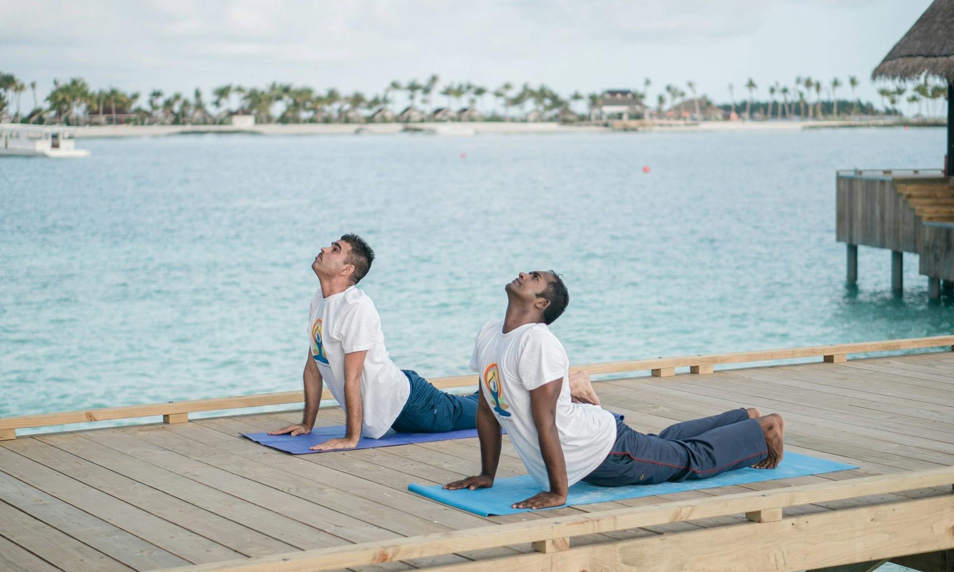 two men doing yoga on a pier water outdoors