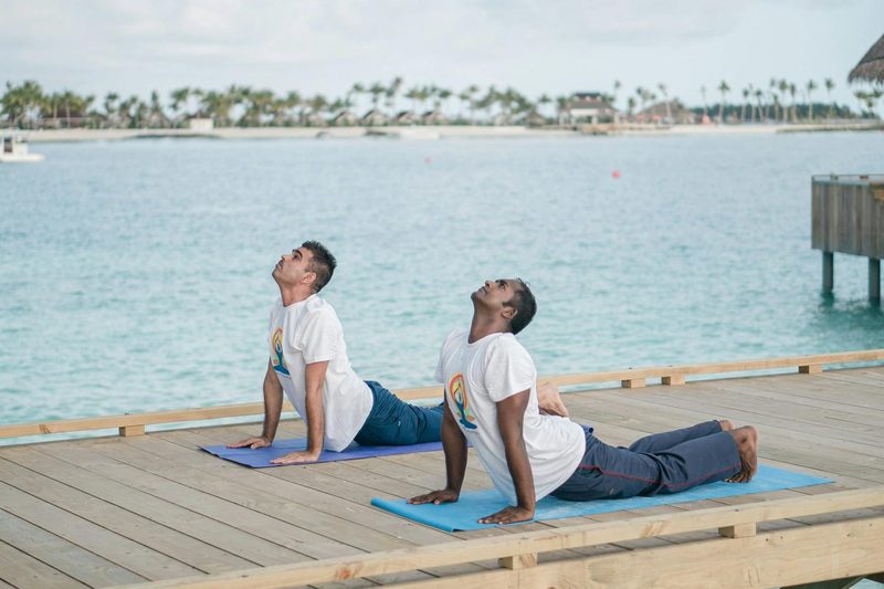 two men doing yoga on a pier water outdoors