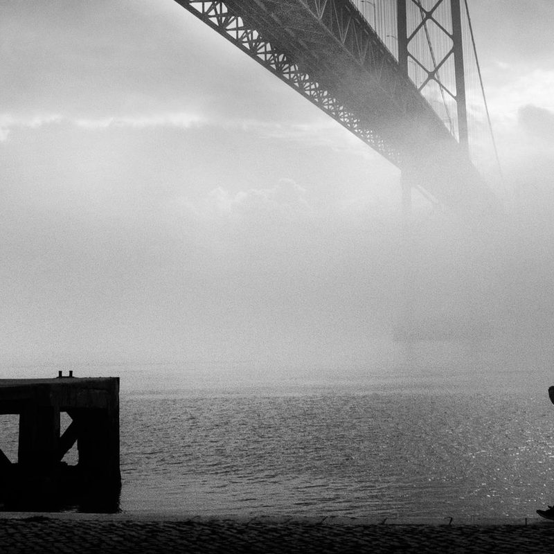Black and white woman silhouette running along the water by the bridge