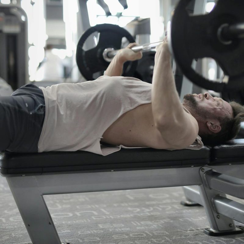 man doing bench press in gym resistance training