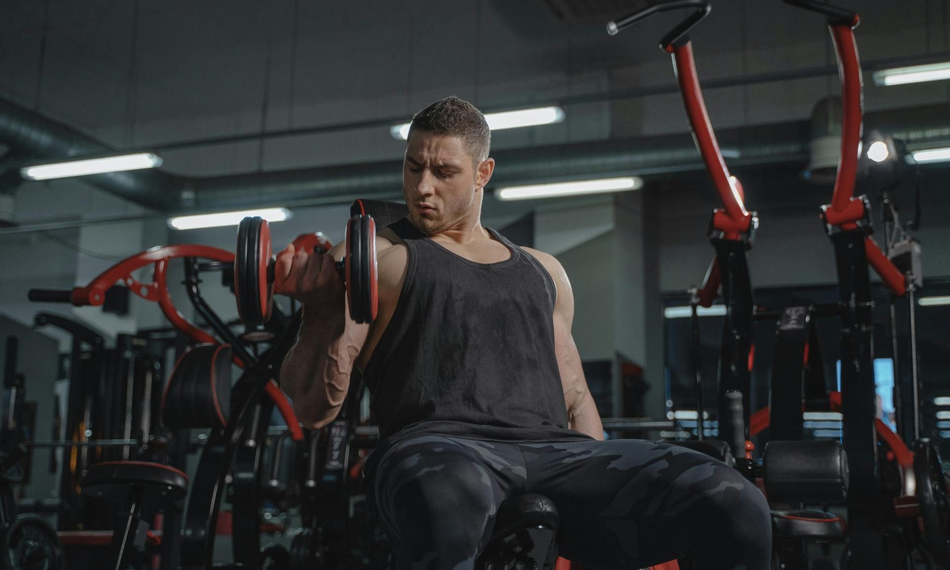 man doing bicep curl in gym one arm unilateral dumbbell.
