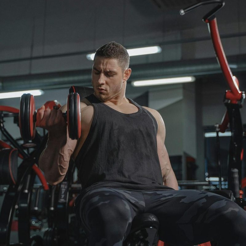 Man doing bicep curl in gym - one arm unilateral with a dumbbell
