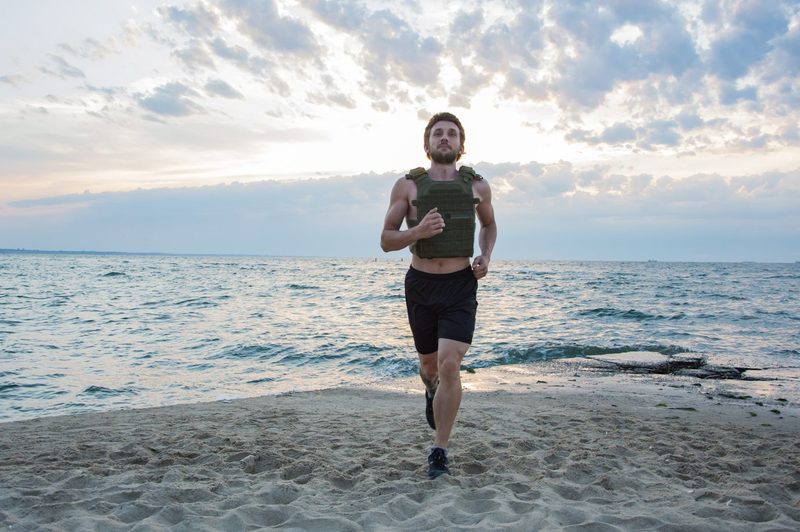 man walking jogging running wearing weighted vest outdoors beach workout