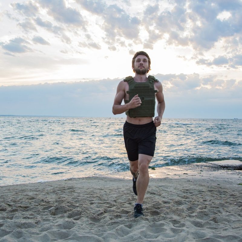 Man walking jogging running wearing weighted vest outdoors beach workout
