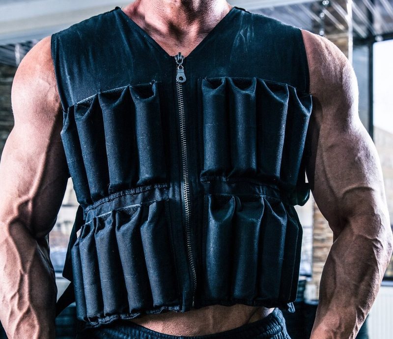 man wearing weighted vest in gym close up arms muscular muscles flex fist clench