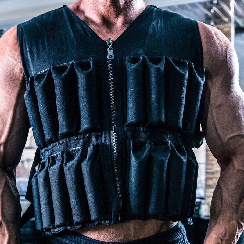 man wearing weighted vest in gym close up arms muscular muscles flex fist clench