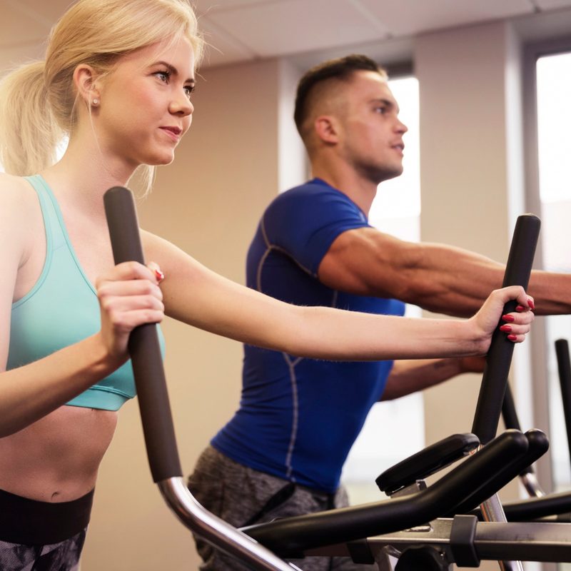 Man and woman using ellipticals
