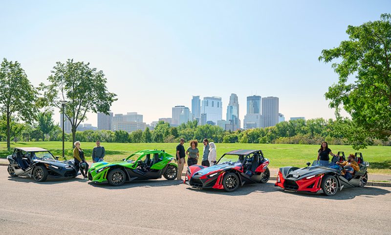 2025 Polaris Slingshot models S, SL, SLR, and R with options in a parking lot with drivers.