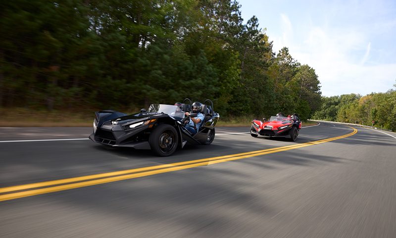 Two 2025 Polaris Slingshot S models driving on a wide open road.