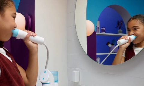 A girl using Willo's AutoFlo Plus in her bathroom mirror.