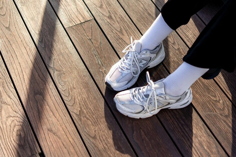 white running shoes with tied laces on wood floor