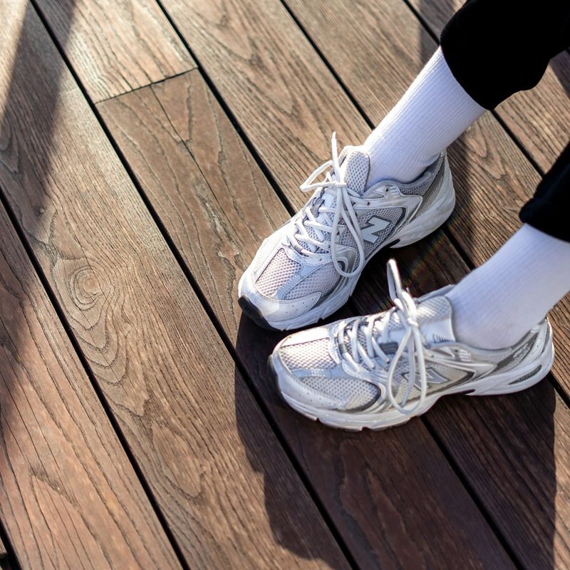 White running shoes with tied laces on wood floor