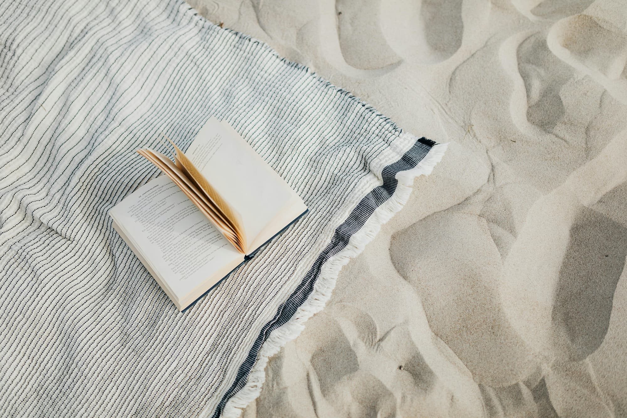 book sitting open on a beach towel outside