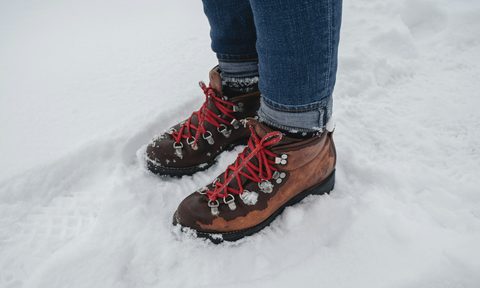Man wearing hiking boots in the snow with red laces