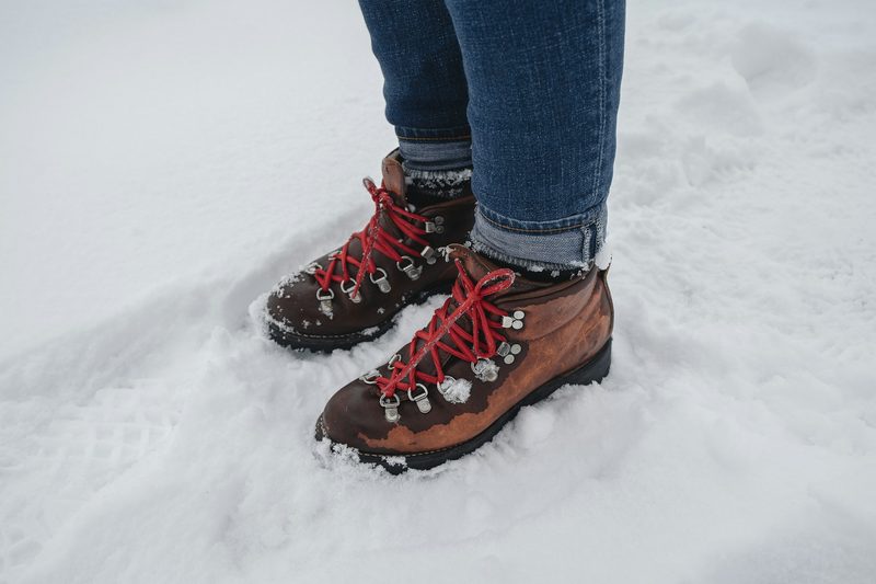 Man wearing hiking boots in the snow with red laces