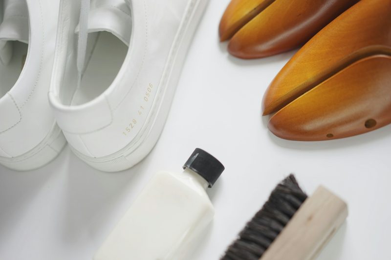 pair of shoes, shoe fill, and shoe brush on a table