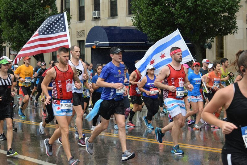 men running in marathon with US flag rainy
