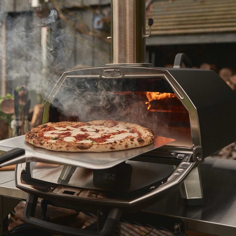 Ooni pizza oven with a freshly cooked pizza still inside of it