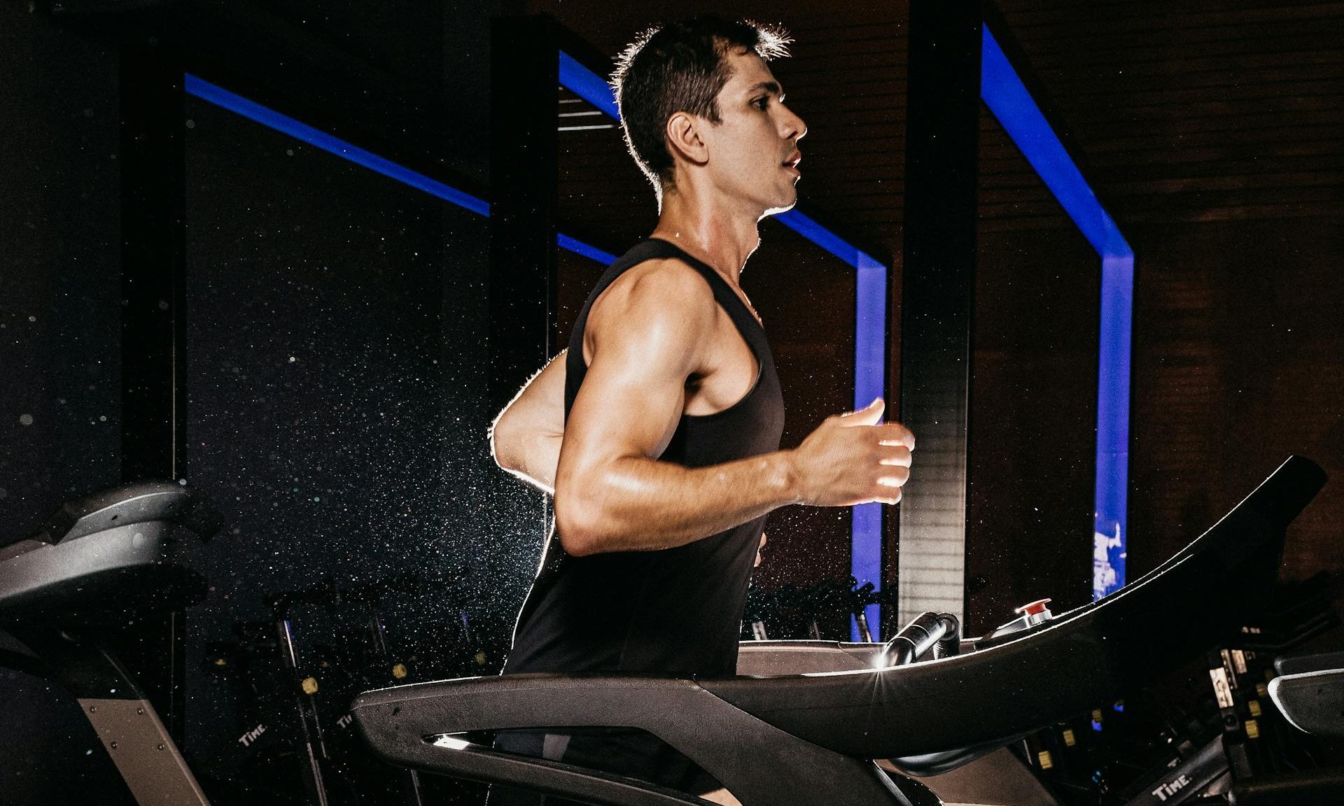 man running wearing black vest on treadmill cardio aerobic