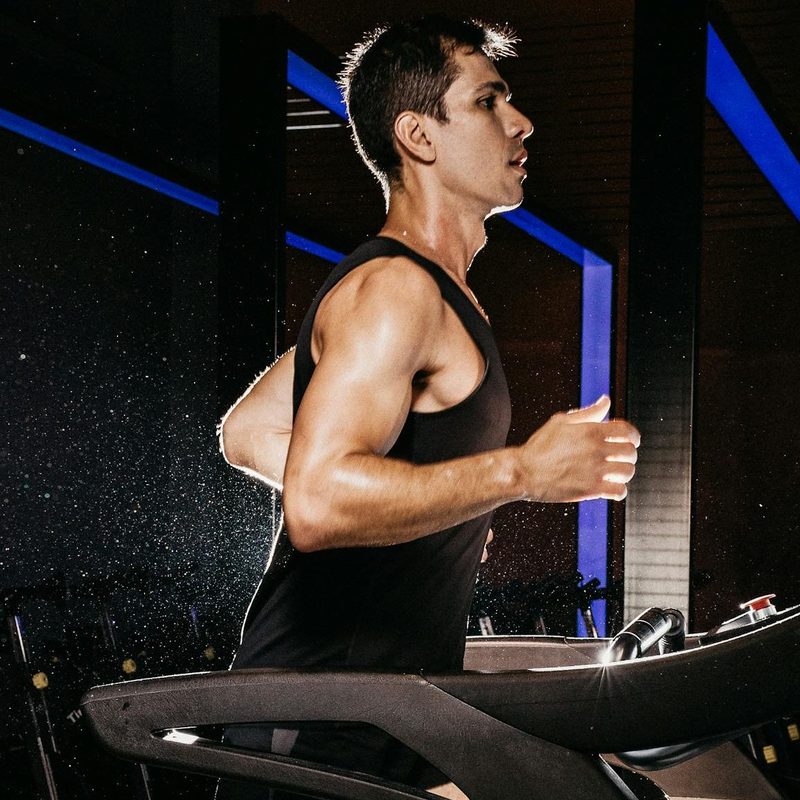 man running wearing black vest on treadmill cardio aerobic