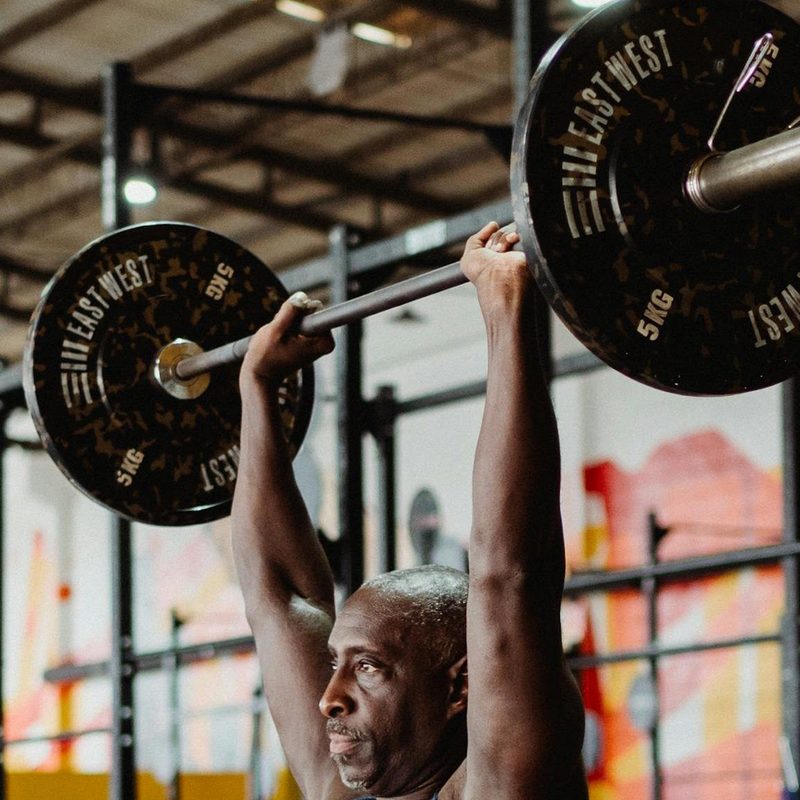 man lifting overhead barbell press in gym