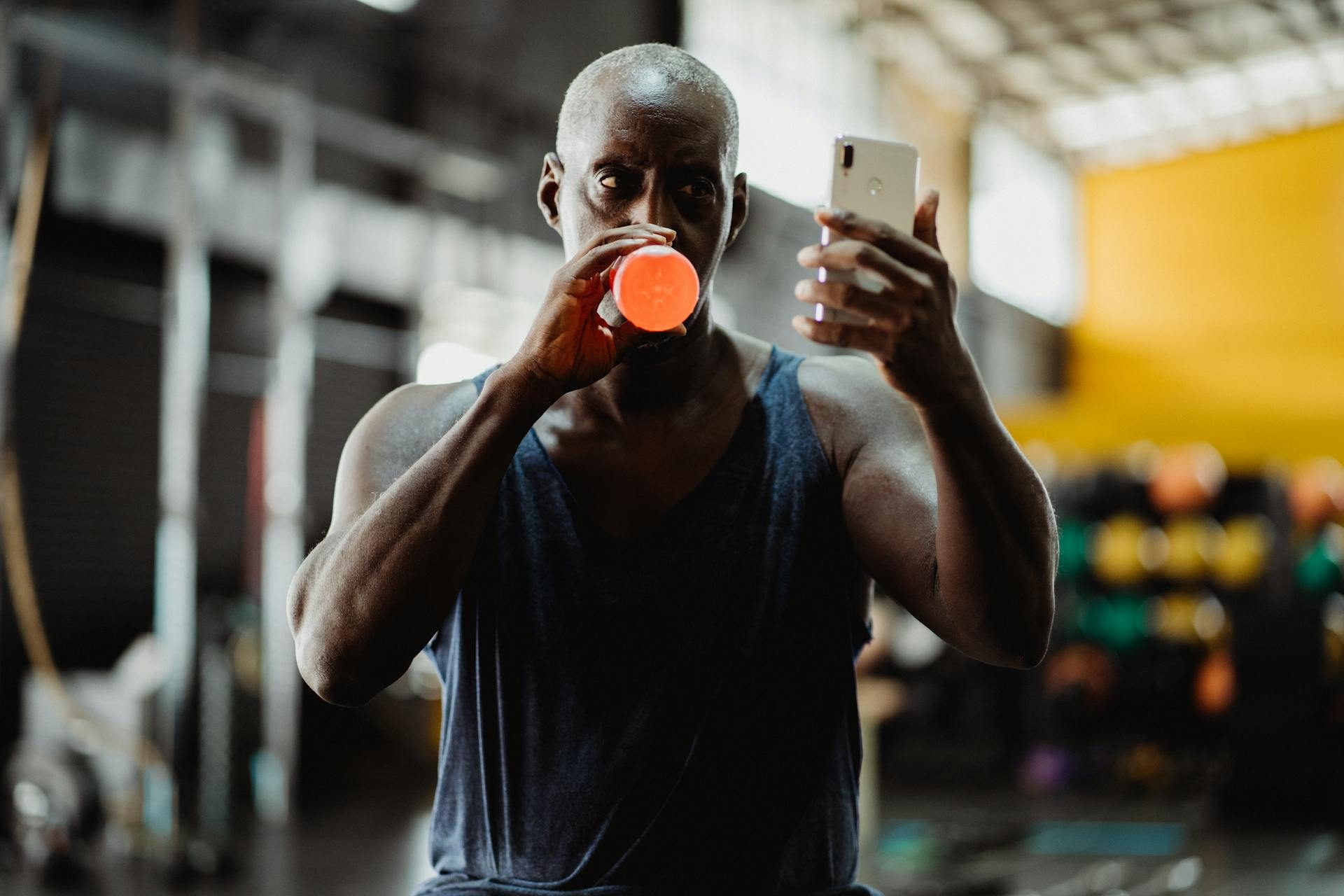man working out taking picture selfie in gym holding phone