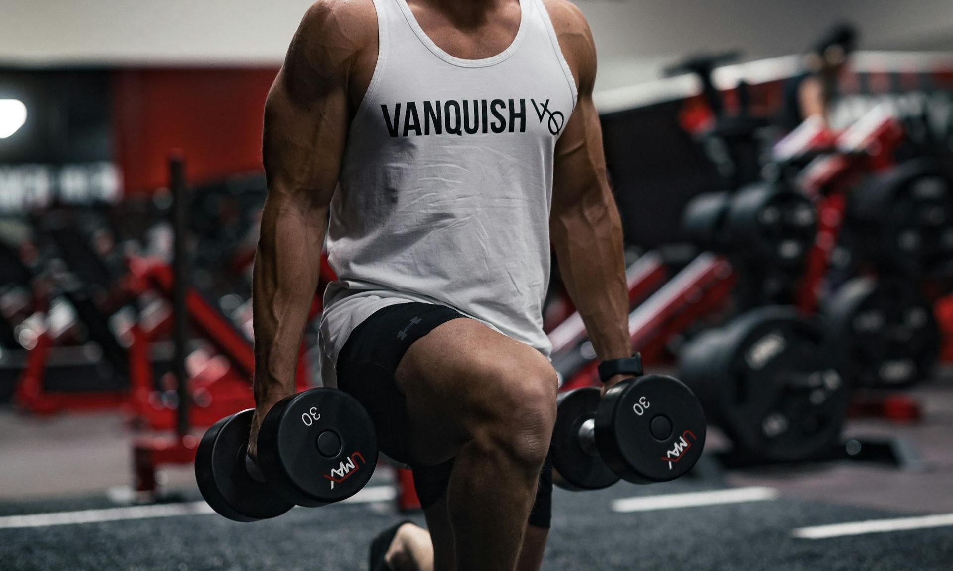 man doing dumbbell lunge in gym