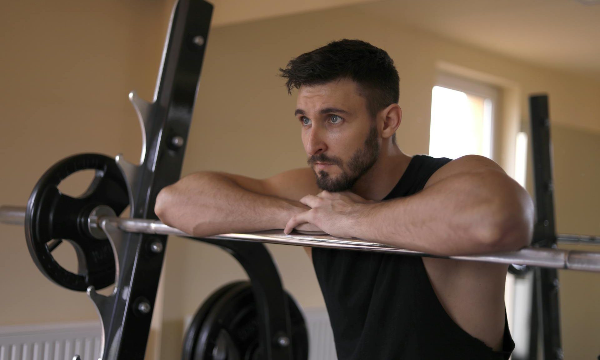 Man leaning on barbell in gym workout home gym
