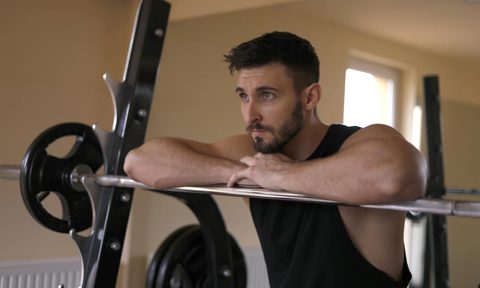 Man leaning on barbell in gym workout home gym