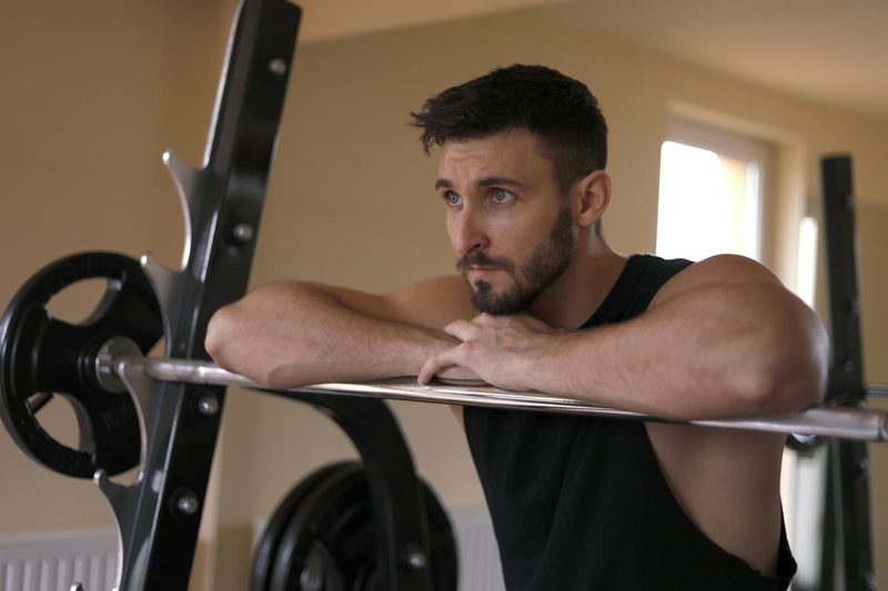Man leaning on barbell in gym workout home gym