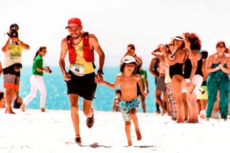 man and son running a marathon together outside on beach