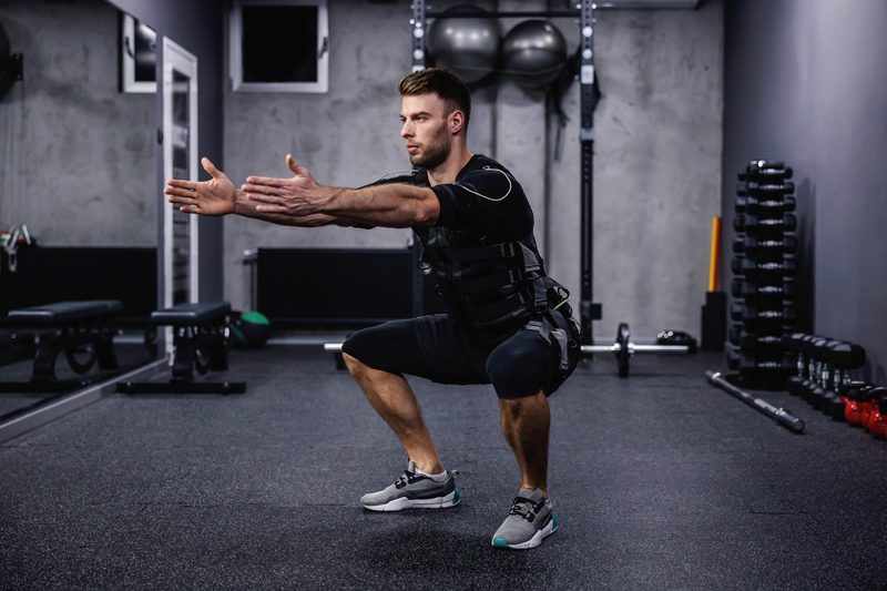 Man squatting with EMS suit on work out exercise