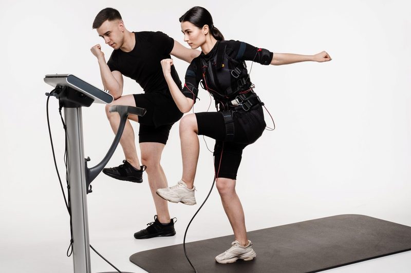 man and woman working out wearing EMS suits electrical muscle stimulation high knees