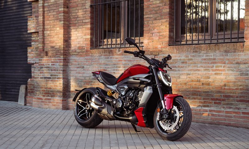 2025 Ducati XDiavel V4 Sport Cruiser parked on a stone lot next to a brick building with iron bar window covers.