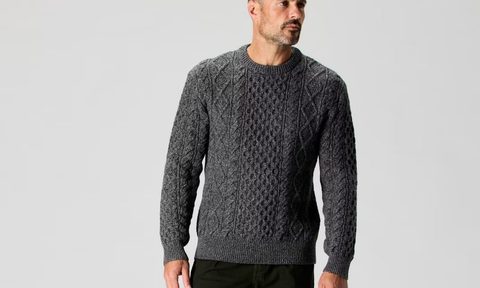 A man wearing a heather charcoal colored Flint and Tinder Aran Cable Sweater.