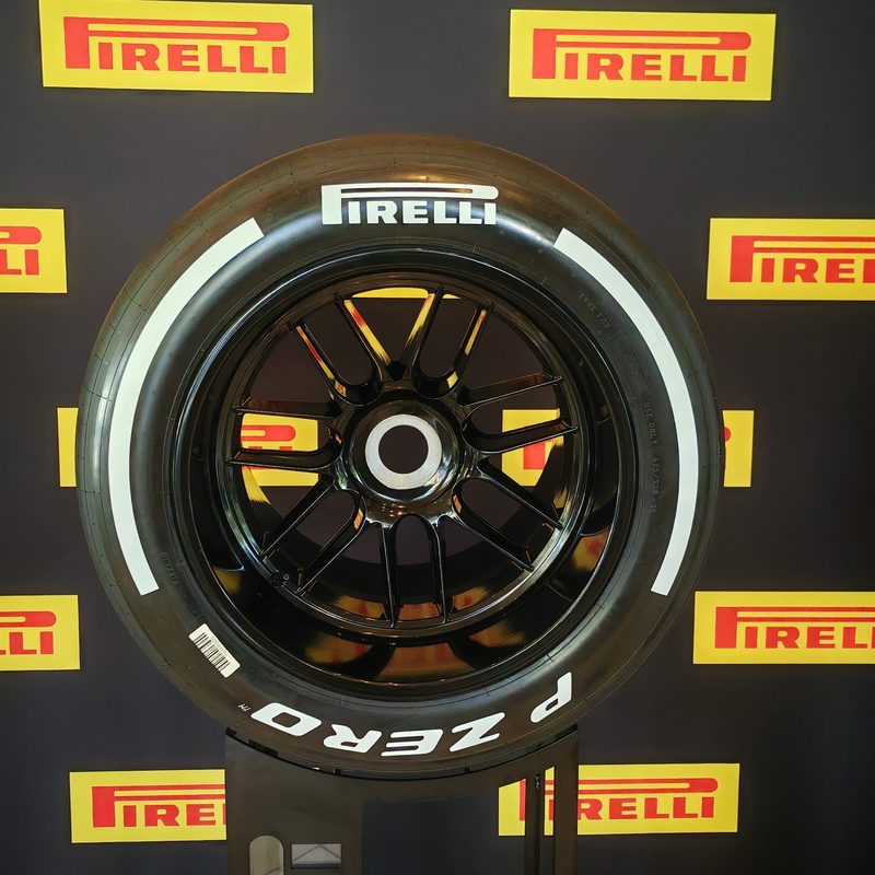 A hard compound F1 tire with white coloring and a Pirelli background