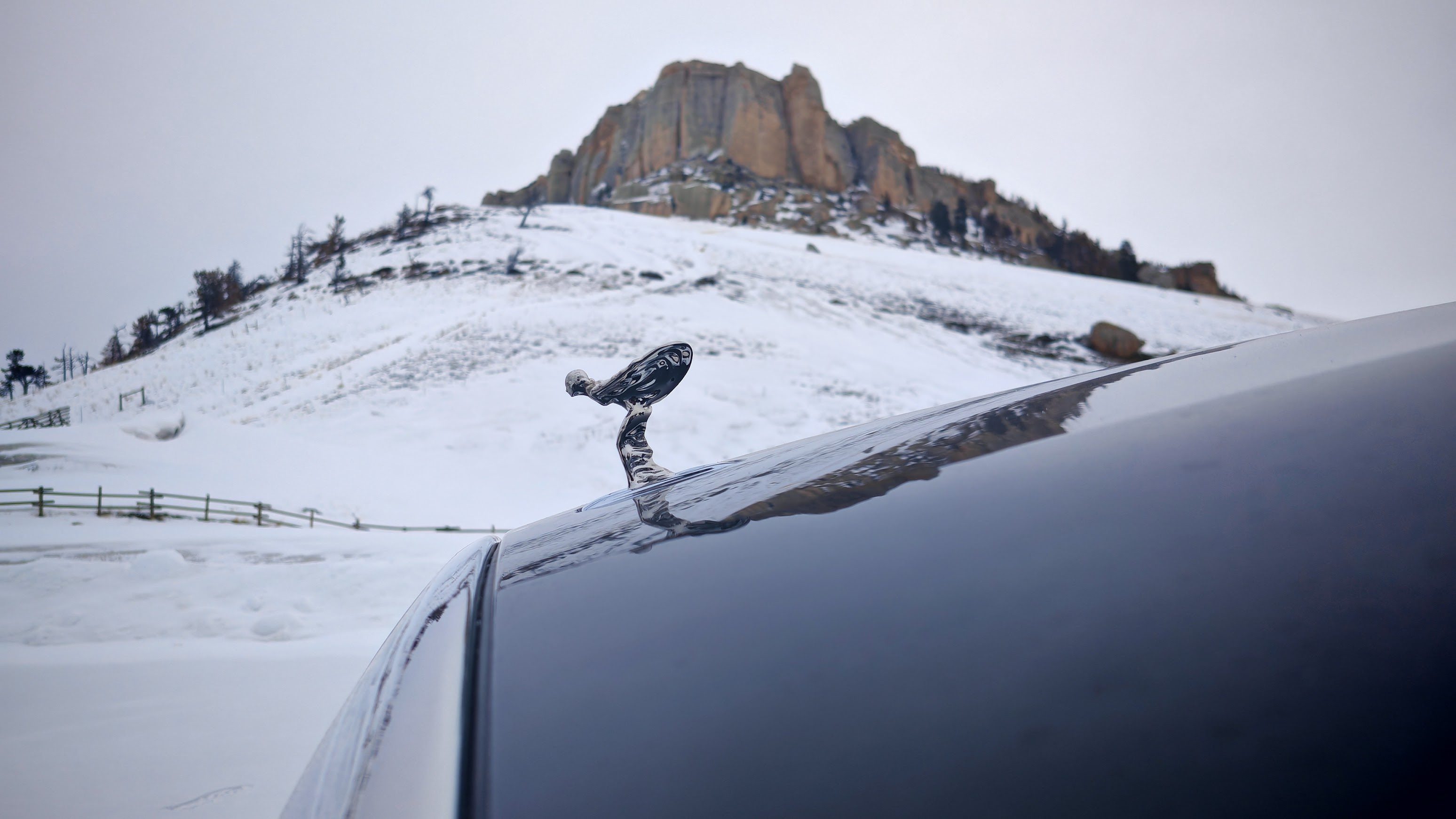 The Spirit of Ecstasy with a mountain in the background attached to a Rolls-Royce Ghost
