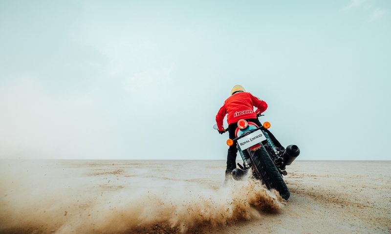Royal Enfield Shotgun 650 limited edition driving away from the camera kicking up sand.