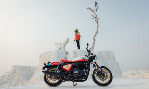 Royal Enfield Shotgun 650 limited edition right side view with rider and a solitary bare tree on a rise in the background in the desert.