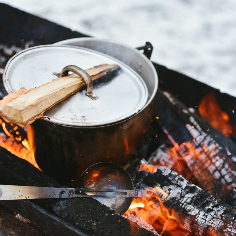 Camping cooking pot warming on hot coals