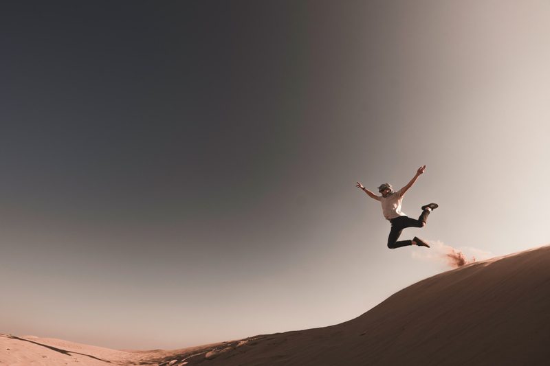 man jumping on desert sand