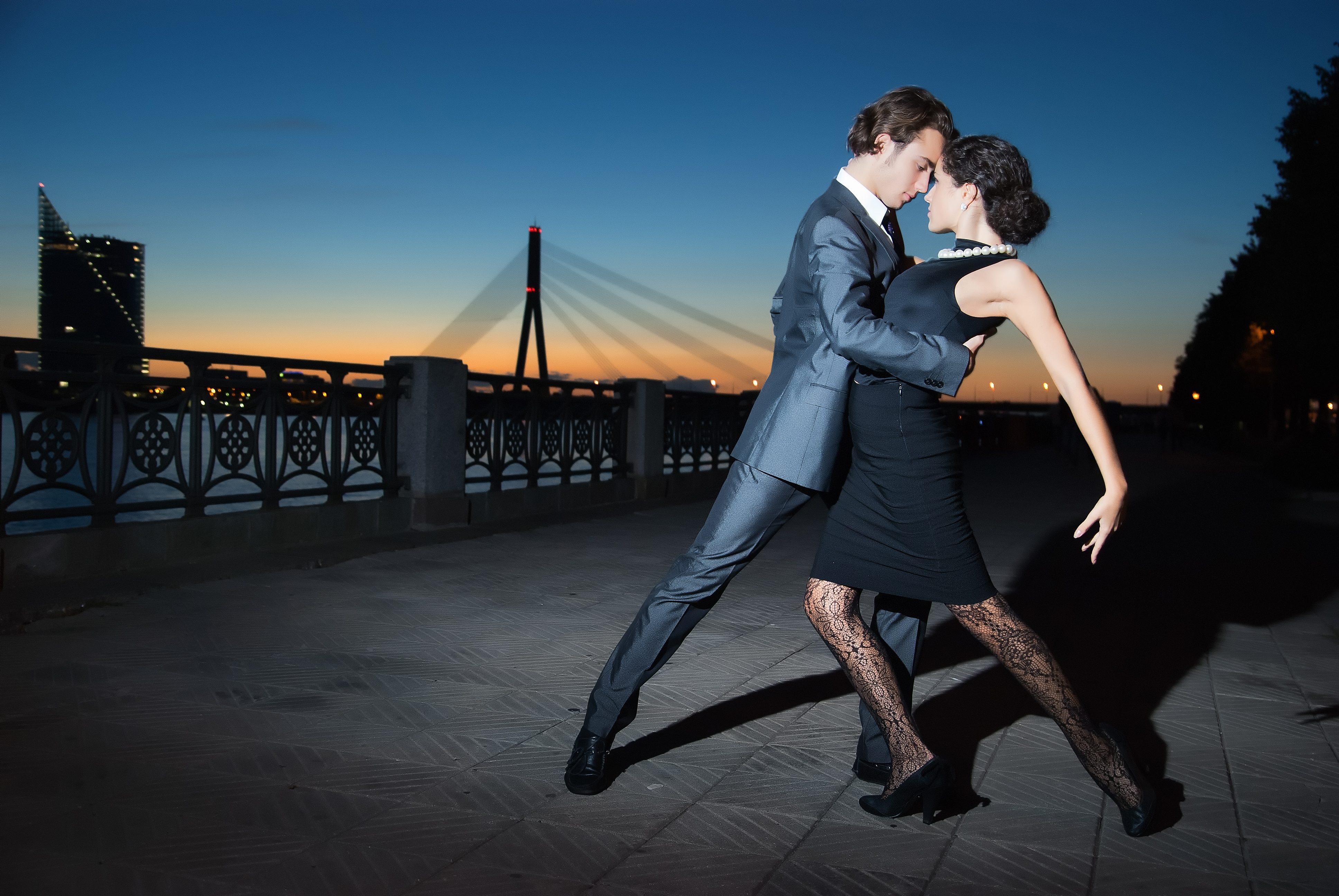 young couple dancing tango on the quay of the river at night