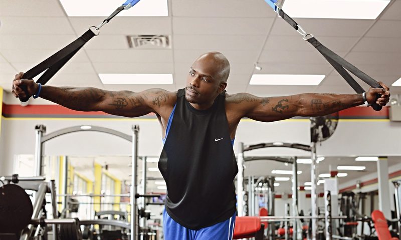 man in gym using bands thinking happy