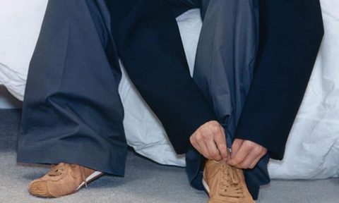 man tying laces on brown suede sneakers